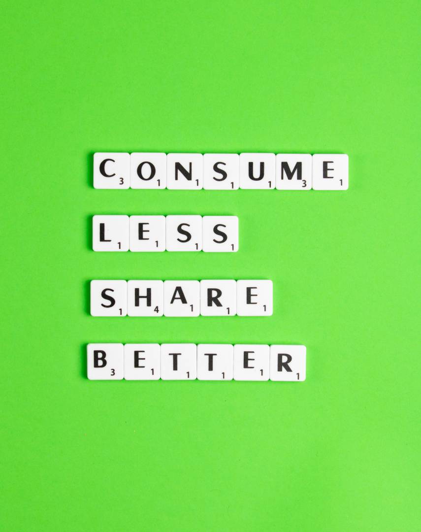 Scrabble Letters On Green Background Saying 'Consume Less Share Better'