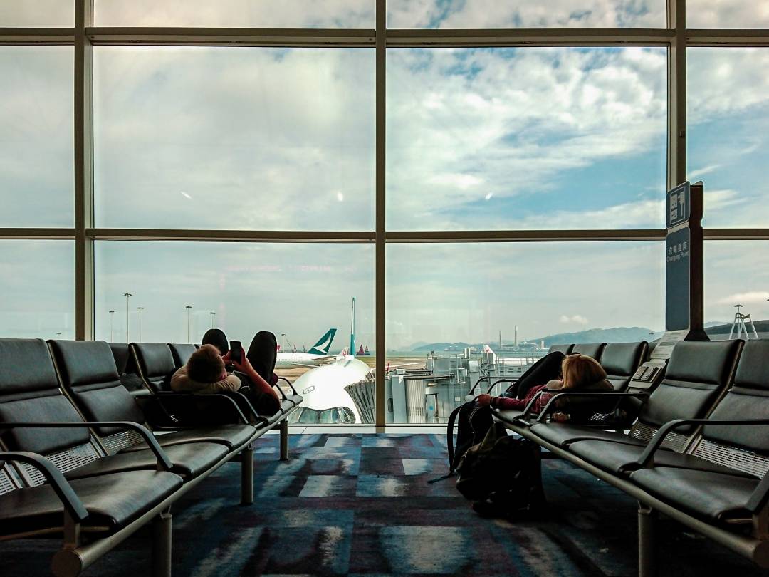 Airport departures lounge with two people lying on a bank of seats