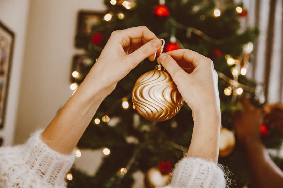 Hanging A Gold Bauble On A Christmas Tree