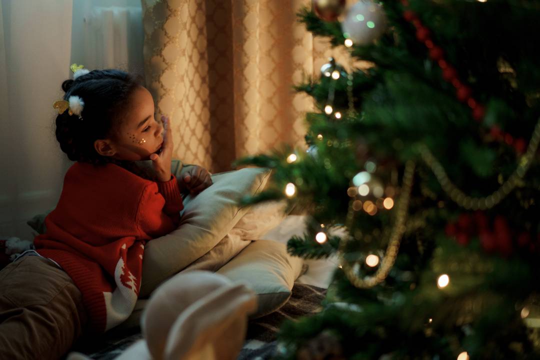 Child Laid Next To A Christmas Tree
