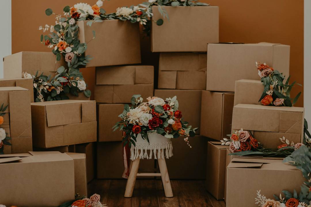 Cardboard boxes stacked on top of each other with flower bouquets placed on a few of them