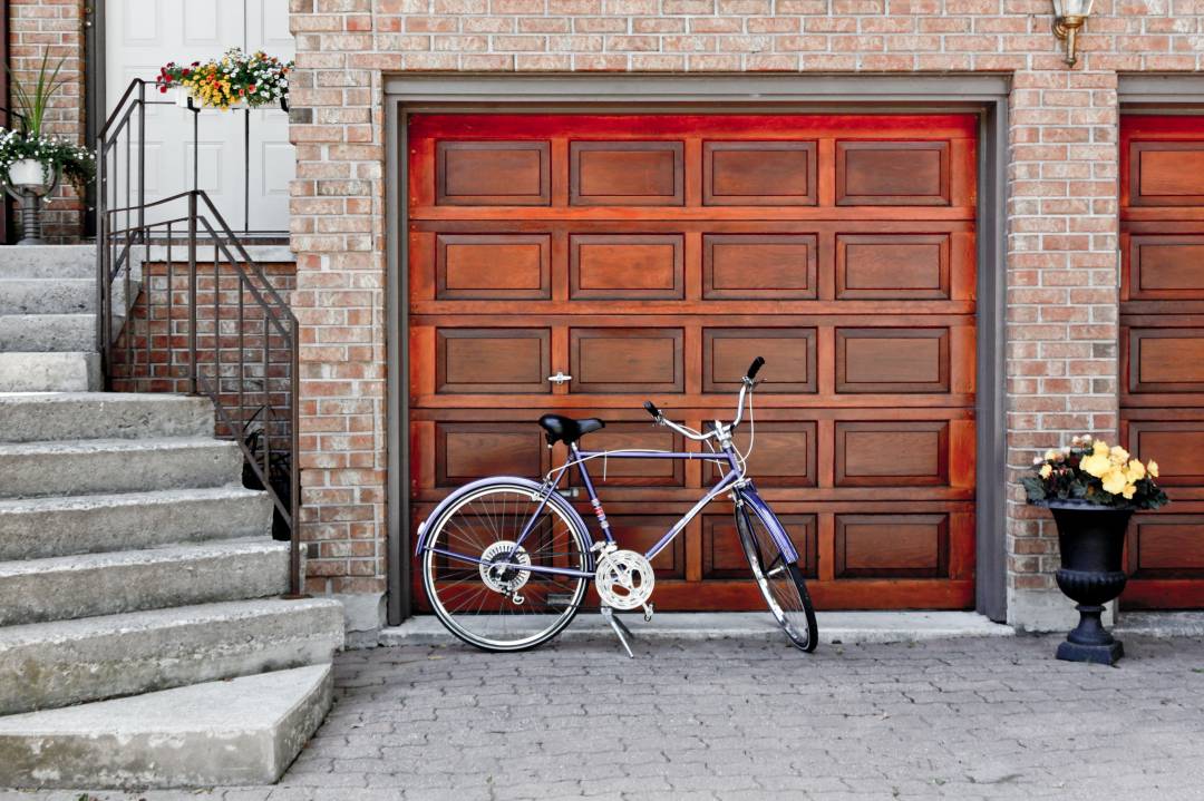 Bicycle in front of a closed garage door next to a set of stairs