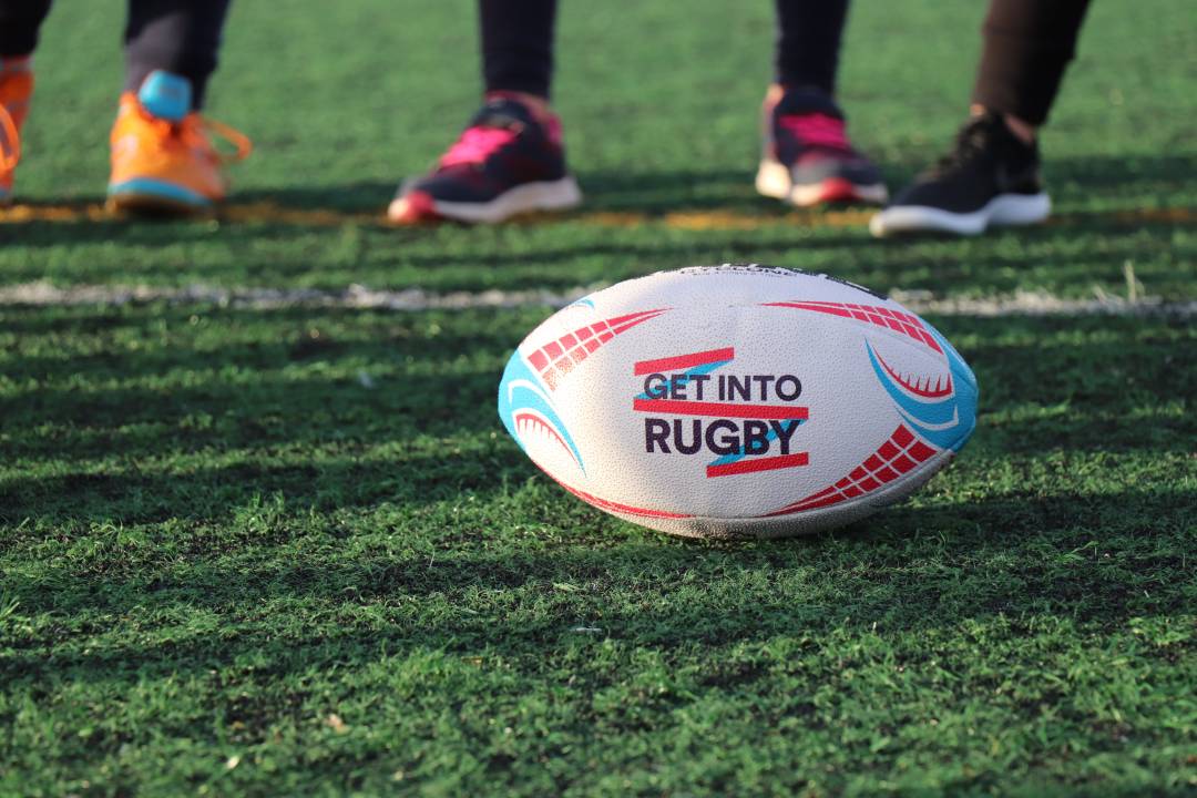 Rugby ball on a pitch with player feet in the background