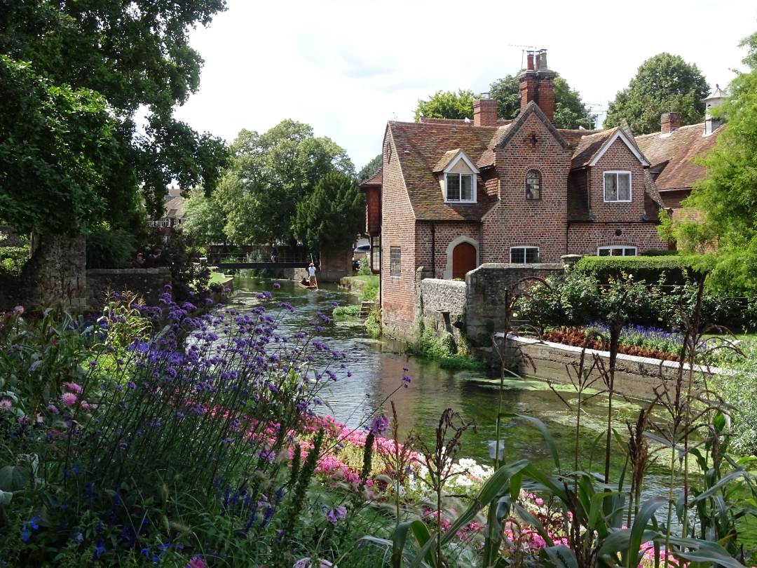 View of a river and a house in Canterbury with flowers in bloom