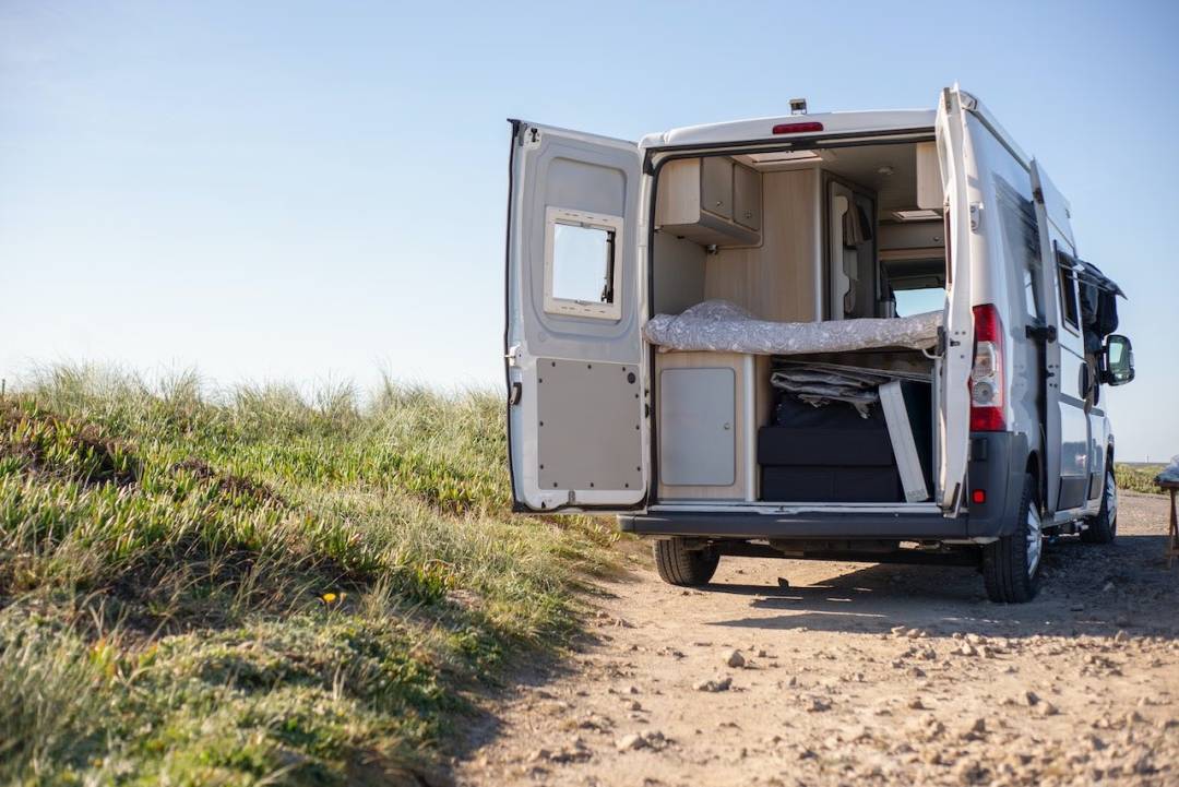 White Campervan On Sandy Track With Doors Open