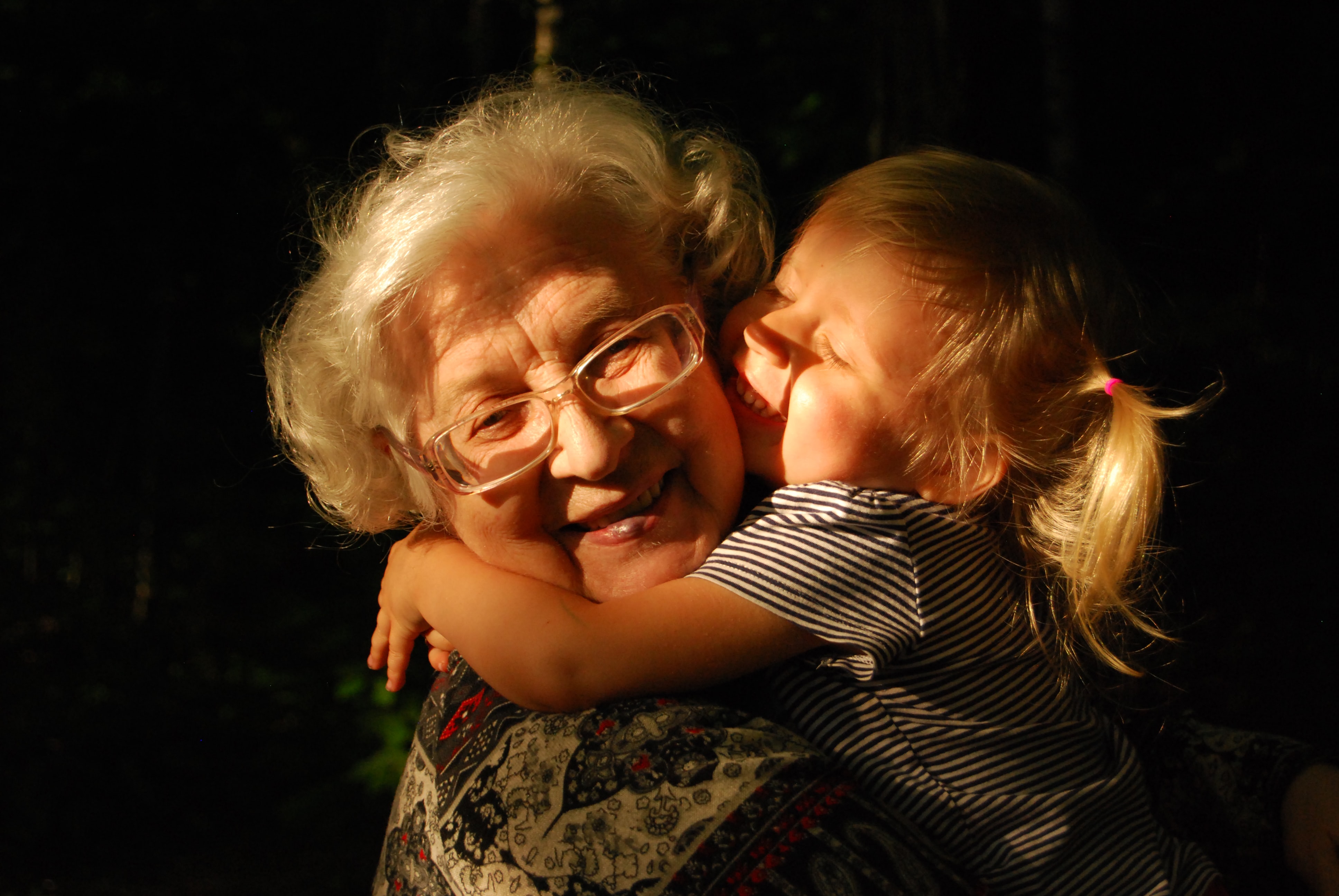 Little girl hugging her grandmother and smiling
